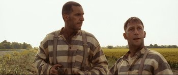 Movie still from “O Brother, Where Art Thou?” (2000), directed by Joel Coen – A man in striped shirt standing next to another man in a field; Close Up shot, Low angle