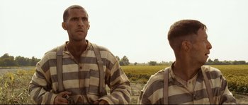 Movie still from “O Brother, Where Art Thou?” (2000), directed by Joel Coen – Two men in striped shirts standing next to each other in a field; Medium shot, Low angle