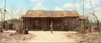 Movie still from “O Brother, Where Art Thou?” (2000), directed by Joel Coen – A person standing in front of an old house; Extreme Wide shot, Low angle