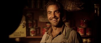 Movie still from “O Brother, Where Art Thou?” (2000), directed by Joel Coen – A man smiling in front of a wall of canned goods; Close Up shot, Low angle