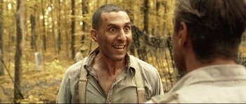 Movie still from “O Brother, Where Art Thou?” (2000), directed by Joel Coen – A person smiling with trees in the background; Close Up shot, Low angle