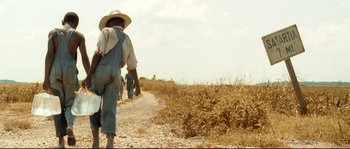 Movie still from “O Brother, Where Art Thou?” (2000), directed by Joel Coen – A man walking down a dirt road in a field; Wide shot, Low angle