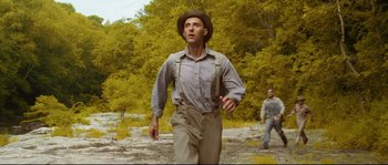 Movie still from “O Brother, Where Art Thou?” (2000), directed by Joel Coen – A man wearing a hat and a shirt is running in the woods; Medium shot, Low angle