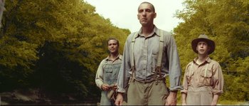 Movie still from “O Brother, Where Art Thou?” (2000), directed by Joel Coen – Two men standing next to each other near a forest; Medium shot, Low angle