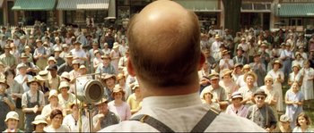 Movie still from “O Brother, Where Art Thou?” (2000), directed by Joel Coen – A man with a beard is standing in front of a group of people; Medium shot, Over the shoulder angle