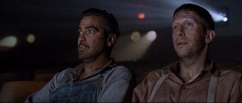 Movie still from “O Brother, Where Art Thou?” (2000), directed by Joel Coen – A man sitting next to another man in front of a window; Close Up shot, Low angle