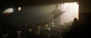 Movie still from “O Brother, Where Art Thou?” (2000), directed by Joel Coen – A man standing in a theater with a microphone; Wide shot, Low angle