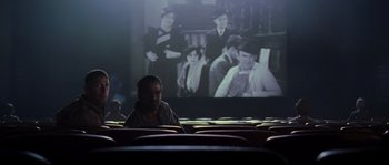 Movie still from “O Brother, Where Art Thou?” (2000), directed by Joel Coen – A woman sitting in front of a movie screen; Wide shot, Over the shoulder angle