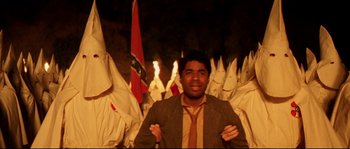 Movie still from “O Brother, Where Art Thou?” (2000), directed by Joel Coen – A man standing in front of a group of people wearing white hoods; Medium shot, High angle