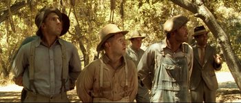 Movie still from “O Brother, Where Art Thou?” (2000), directed by Joel Coen – A group of men standing next to each other in the woods; Medium shot, Low angle