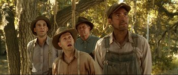 Movie still from “O Brother, Where Art Thou?” (2000), directed by Joel Coen – A group of men standing next to each other in a forest; Medium shot, Low angle