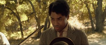 Movie still from “O Brother, Where Art Thou?” (2000), directed by Joel Coen – A man in a suit and tie holding a rifle; Close Up shot, Low angle