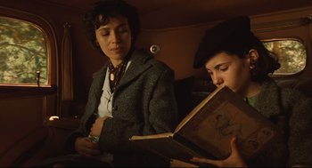 Movie still from “Pan's Labyrinth” (2006), directed by Guillermo del Toro – Two people sitting on a train looking at a book; Medium shot, Low angle