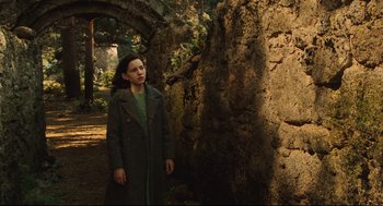 Movie still from “Pan's Labyrinth” (2006), directed by Guillermo del Toro – A girl in a green coat standing next to a tree; Wide shot, Over the shoulder angle