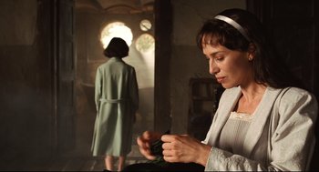 Movie still from “Pan's Labyrinth” (2006), directed by Guillermo del Toro – A woman in a white dress is looking down at a piece of paper in her hand; Medium shot, Over the shoulder angle