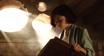 Movie still from “Pan's Labyrinth” (2006), directed by Guillermo del Toro – A woman holding an open book in a dimly - lit room; Medium shot, Low angle