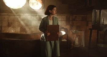 Movie still from “Pan's Labyrinth” (2006), directed by Guillermo del Toro – A woman holding a book while standing in a room; Medium shot, Low angle