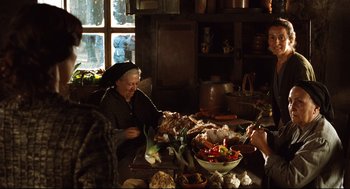 Movie still from “Pan's Labyrinth” (2006), directed by Guillermo del Toro – An old woman sitting at a table with a bowl of food; Medium shot, Over the shoulder angle