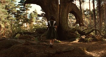 Movie still from “Pan's Labyrinth” (2006), directed by Guillermo del Toro – A woman in a dress standing in front of a tree; Wide shot, Low angle