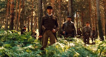 Movie still from “Pan's Labyrinth” (2006), directed by Guillermo del Toro – A group of men standing in the woods holding guns; Medium shot, Low angle