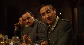 Movie still from “Pan's Labyrinth” (2006), directed by Guillermo del Toro – A group of men sitting next to each other in uniforms; Medium shot, Over the shoulder angle