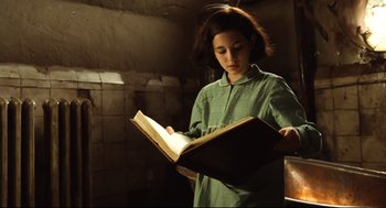 Movie still from “Pan's Labyrinth” (2006), directed by Guillermo del Toro – A young girl is reading a book in the dark; Medium shot, Low angle