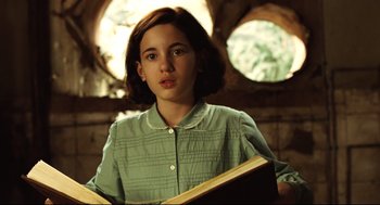 Movie still from “Pan's Labyrinth” (2006), directed by Guillermo del Toro – A young girl holding an open book while standing in front of a window; Close Up shot, Low angle