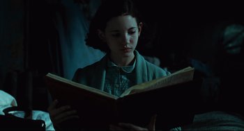 Movie still from “Pan's Labyrinth” (2006), directed by Guillermo del Toro – A girl is reading a book in a dark room; Close Up shot, Low angle