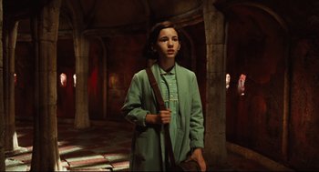 Movie still from “Pan's Labyrinth” (2006), directed by Guillermo del Toro – A woman in a green coat holding a brown bag; Medium shot, High angle