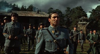 Movie still from “Pan's Labyrinth” (2006), directed by Guillermo del Toro – A group of men in uniform standing in front of a building; Medium shot, Low angle