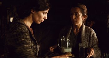 Movie still from “Pan's Labyrinth” (2006), directed by Guillermo del Toro – Two women are holding a tray of food and drinking milk; Medium shot, Over the shoulder angle
