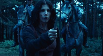 Movie still from “Pan's Labyrinth” (2006), directed by Guillermo del Toro – A woman holding a knife in front of two horses; Medium shot, Low angle