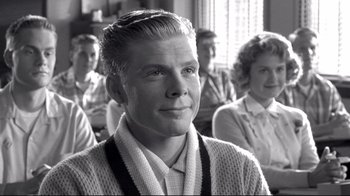 Movie still from “Pleasantville” (1998), directed by Gary Ross – An older man is smiling in front of a group of people; Close Up shot, Over the shoulder angle