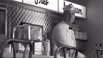 Movie still from “Pleasantville” (1998), directed by Gary Ross – A black and white photo of a man sitting at a counter; Medium shot, Low angle