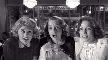Movie still from “Pleasantville” (1998), directed by Gary Ross – A group of women standing next to each other in front of a building; Close Up shot, Low angle