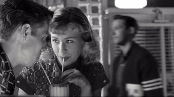 Movie still from “Pleasantville” (1998), directed by Gary Ross – A woman drinking a drink while standing next to a man; Close Up shot, Low angle