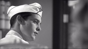 Movie still from “Pleasantville” (1998), directed by Gary Ross – A man wearing a sailor's hat looking to his left; Close Up shot, Low angle