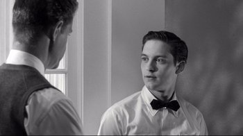 Movie still from “Pleasantville” (1998), directed by Gary Ross – A man in a white dress shirt and bow tie looking at himself in the mirror; Close Up shot, Over the shoulder angle