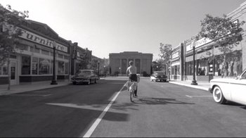 Movie still from “Pleasantville” (1998), directed by Gary Ross – A man riding a bike down the middle of a street; Extreme Wide shot, High angle