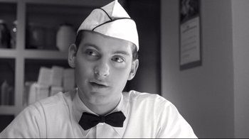 Movie still from “Pleasantville” (1998), directed by Gary Ross – A man wearing a paper hat and a bow tie; Close Up shot, Low angle