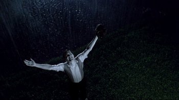 Movie still from “Pleasantville” (1998), directed by Gary Ross – A man holding a baseball in the rain with his arms outstretched; Medium shot, Overhead angle