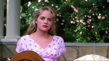 Movie still from “Pleasantville” (1998), directed by Gary Ross – A woman in a pink dress is sitting in front of some flowers; Close Up shot, Over the shoulder angle