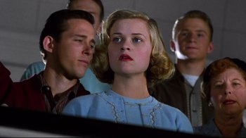 Movie still from “Pleasantville” (1998), directed by Gary Ross – A woman in a blue dress is in front of a group of men; Close Up shot, Low angle