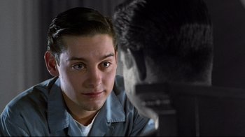 Movie still from “Pleasantville” (1998), directed by Gary Ross – A young man looking at the camera with his reflection in the mirror; Close Up shot, Over the shoulder angle