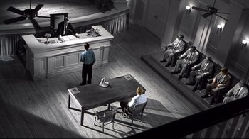 Movie still from “Pleasantville” (1998), directed by Gary Ross – Two men are sitting at a table in front of a judge; Wide shot, High angle