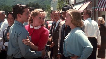 Movie still from “Pleasantville” (1998), directed by Gary Ross – A group of people standing next to each other on the street; Medium shot, Over the shoulder angle