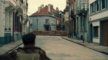 Movie still from “Dunkirk” (2017), directed by Christopher Nolan – A man is walking down the street in a city; Extreme Wide shot, High angle