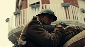 Movie still from “Dunkirk” (2017), directed by Christopher Nolan – A man wearing a helmet and holding a rifle; Medium shot, Low angle