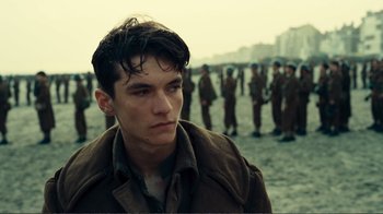Movie still from “Dunkirk” (2017), directed by Christopher Nolan – A young man standing in front of a group of soldiers; Close Up shot, Over the shoulder angle