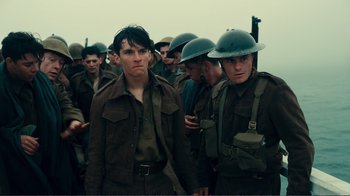 Movie still from “Dunkirk” (2017), directed by Christopher Nolan – A group of men in military fatigues standing together; Medium shot, Low angle